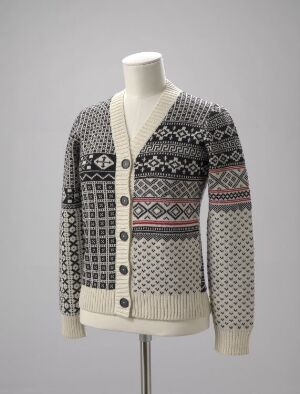  A traditional Scandinavian-style knitted cardigan on a female mannequin featuring off-white as the primary color with black, gray, and soft red patterned designs, set against a neutral gray background.