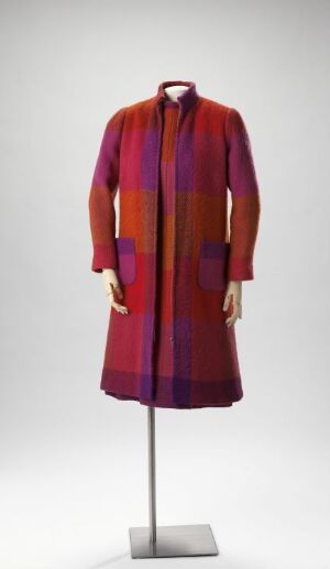  A mannequin displaying a knee-length coat with a high neckline and a vibrant red and purple checkered pattern against a plain background.