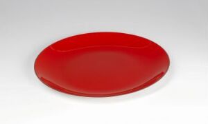  A shallow, oval-shaped red plate with a glossy enamel finish made of stainless steel, designed by Cathrineholm.