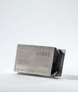  "Norsk folkemedisin – Anabole Steroider" by Konrad Mehus, an artwork mimicking a crumpled medicine package made from etched and silver-plated brass with detailed text and barcode designs on its surface, set against a plain white backdrop.