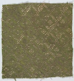  Textured olive green fabric with intricate pale patterns reminiscent of floral designs, showcasing uneven and frayed edges with a natural, aged appearance. Artist and title are unknown.