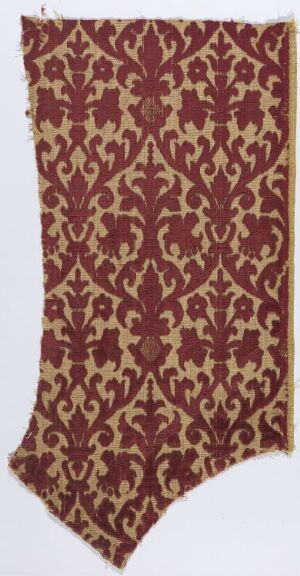  An ornate fabric fragment with a deep red background and a warm beige floral and vine-like pattern, demonstrating a traditional or historical textile design.