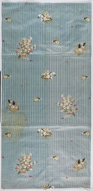  A vertical textile panel with a muted blue background featuring vertical textured lines and a pattern of alternating large and small clusters of delicately embroidered flowers in pastel and earth tones, with hints of metallic gold.