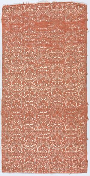  An elongated, rectangular coral-colored textile with intricate, repetitive floral patterns in a lighter ivory or pale gold hue, suggesting a finely crafted rug or tapestry with traditional ornamental design.