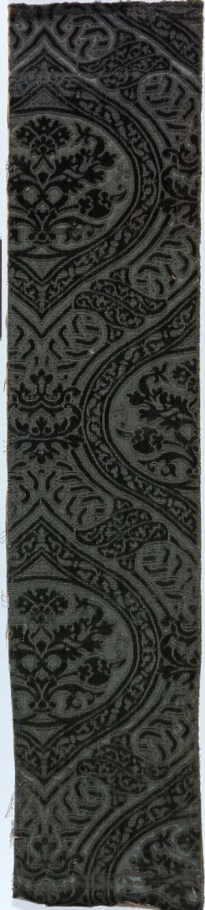  A narrow vertical image displaying a monochromatic, intricate lace-like pattern in shades of dark grey and black, with a repeating design that features interlocking curved and diamond shapes.