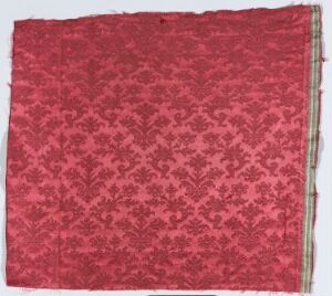  A textile sample featuring a repetitive floral pattern in varying shades of red with one neat golden-colored border, indicating an artistic exploration of monochromatic design in fabric.