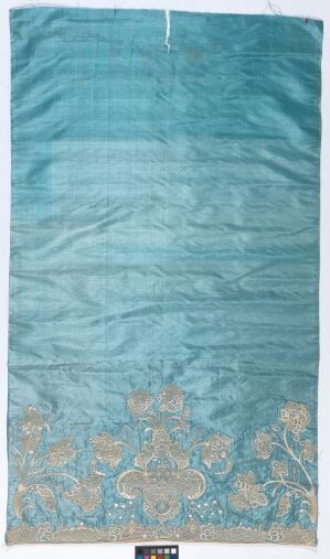  A vertical tapestry or rug with a serene blue background, featuring a decorative floral motif in lighter hues at the bottom. The piece exudes a calm elegance and showcases traditional craftsmanship.