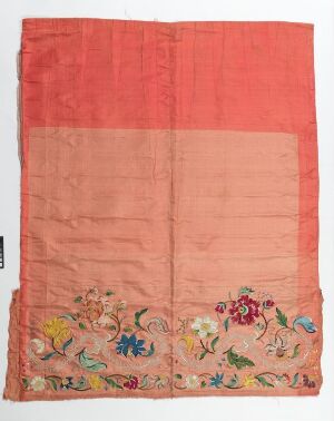  A rectangular fabric piece with the top half in a coral-red and the bottom in a lighter peach-pink, adorned with colorful embroidered flowers and birds at the lower end.