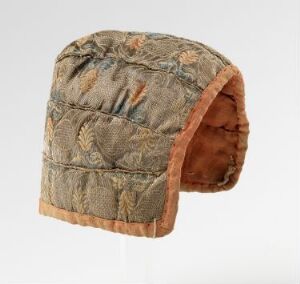  A quilted cap with an earth tone botanical pattern and peach-colored trim set against a light gray background.