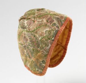  A historic or traditional rounded hat with a detailed green, brown, and muted red foliage pattern, coral trim, and an orange lining. Artist name and title unknown.