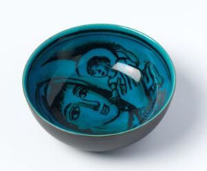  A vibrant cobalt blue bowl with steep sides featuring an illustration of a woman holding a child inside, depicted in a lighter shade of blue, set against an off-white background.