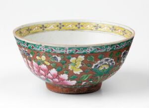  A Bencharong porcelain bowl with overglaze enamel decoration, featuring a deep emerald green exterior adorned with elaborate pink and white floral patterns and a white interior. Artist unknown.