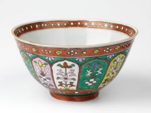  A traditional Bencharong porcelain bowl with a wide rim and footed base, intricately decorated with overglaze enamel colors in red, green, white, and hints of gold, featuring paneled floral or botanical designs on the outer surface.