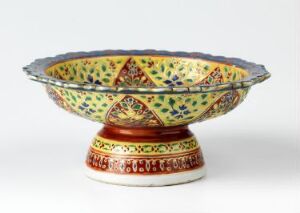  An ornate Bencharong porcelain bowl with a flared rim and pedestal base, featuring richly colored, traditional Thai overglaze enamel decorations with gold detailing.