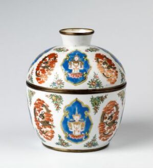  A traditional Bencharong porcelain vessel with a domed lid, adorned with overglaze enamel colors and bronze bands, featuring panels of mythical figures and floral motifs in a vibrant palette of blue, orange, green, and white. Artist name and title of the piece are unknown.