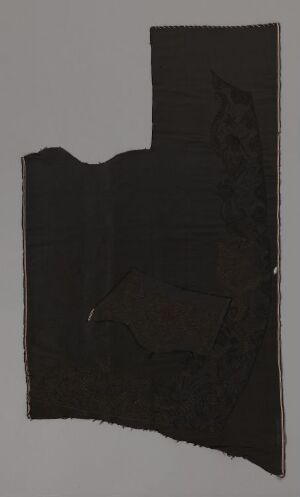  An irregularly shaped dark textured piece that appears to be a fragment of material, predominantly black with subtle variations in shade, set against a flat gray background. The artist's name and title are unknown.