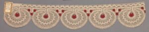  A horizontal piece of delicate off-white lace with an intricate floral pattern, accented with red and burgundy details against a muted background.