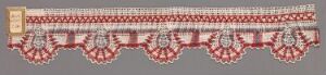  A decorative textile strip with a series of symmetrical red and white diamond and floral motifs on a grey background.