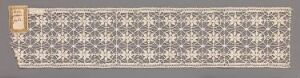  A horizontal strip featuring a recurring symmetrical pattern in shades of grey and white, with a distinct golden square seal in the upper left corner against a neutral grey background. Artistname and title are unknown.