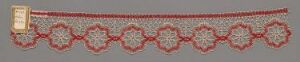  A long, decorative ribbon with a beige background featuring a repeating pattern of red interlocking heart-like shapes with smaller red floral connectors, bordered by thin lines, and a bright yellow label on the left end.