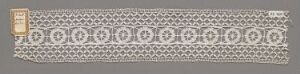  Antique grey-brown textile with symmetrical white embroidery, featuring alternating geometric diamond and ring patterns, suggesting intricate craftsmanship.