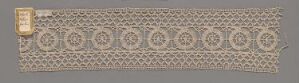  A narrow strip of textile featuring a symmetrical pattern with alternating ovals and diamonds, accented with a rectangular gold-toned embellishment on the left, against a neutral background giving an antique appearance. Artistname and title are unknown.