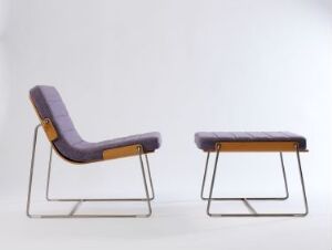  Modern Scandinavian furniture by Norway Says, featuring a purple wool upholstered lounge chair with an oak veneer finish and accompanying ottoman, both with chromed steel frames, set against a light grey background.