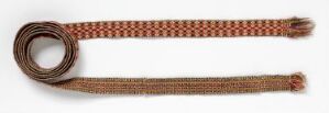  An intricately woven strap or belt with a rolled end, featuring geometric patterns in brown, red, and yellow tones against a light background.