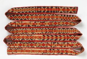  Six intricately patterned textile bands in rusty red with geometric designs in a mix of white, black, orange, and brown, arranged parallel and flat on a white background.