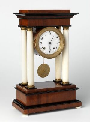  Antique mantel clock with a mahogany wooden base and pediment, creamy white columns, a white dial with black Roman numerals, and a golden bezel and pendulum visible through a small glass window.