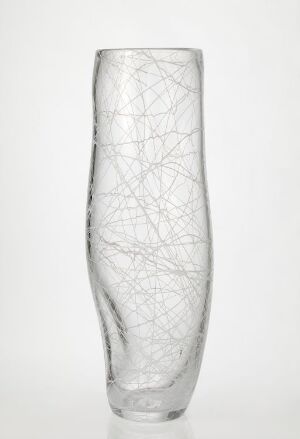  A tall, clear glass vase by Kari Håkonsen titled "Hvit linje", adorned with a delicate white thread decoration that creates a web-like pattern throughout its surface, set against a white background.