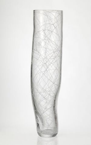  "Hvit linje," a blown glass vase with white thread decoration by Kari Håkonsen, featuring a clear body with intricate white crisscross patterns creating a diamond-like appearance, and a base slightly broader than the tapering top.