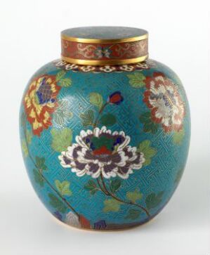  An ornamental vase with a glossy turquoise blue finish and a golden rim, adorned with intricate floral patterns, featuring a prominent white flower with green and pink accents, surrounded by smaller flowers and leaves in oranges, purples, yellows, and greens.