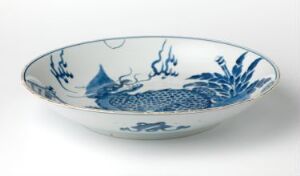  A porcelain bowl with a blue and white design featuring floral motifs and a central dragon figure on a plain white background. Artist and title unknown.