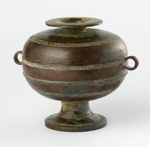  An ancient bronze vessel with a globular body, horizontal bands, two loop handles, and a flat-rimmed neck, displaying a greenish-brown patina against a neutral background.