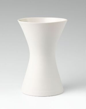  "Comfort living," a turned and unglazed porcelain vase by Andreas Engesvik, featuring a modern, conical, hourglass shape in a soft white color against a gradient gray background.