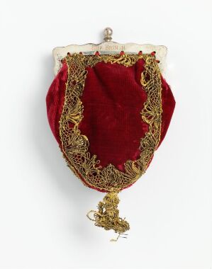  An antique red velvet evening bag with ornate gold embroidery and a tassel hanging from the bottom against a white background.