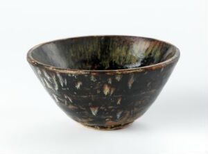  A dark-glazed ceramic bowl with an irregular pattern of lighter tan speckles, displayed on a white background.