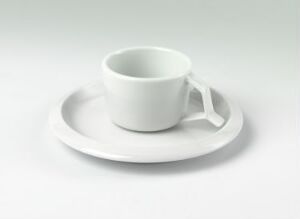  A white feldspar porcelain cup and saucer set designed by Norway Says, displayed on a neutral background. The cup has a sleek, glossy finish with a U-shaped handle, and the saucer has a gentle rim and curve, reflecting simplicity and modern design.