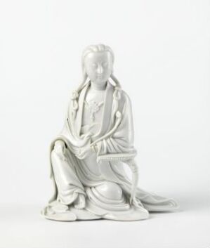  A white glazed porcelain figurine of Guanyin seated in a position of contemplation, dating from the Qianlong period. The figure exhibits detailed craftsmanship, with a flowing robe and serene expression, set against a plain background to emphasize its elegance and artistry.