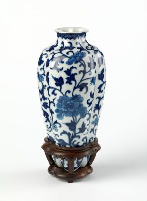  A blue and white porcelain vase with floral designs, displayed on a small carved wooden stand.