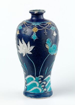  An artistically decorated vase with a deep navy blue background featuring white and turquoise floral patterns and gold accent lines, crafted with a glossy finish. The vase tapers towards the base and has a slightly narrowed neck. Artist name and title unknown.