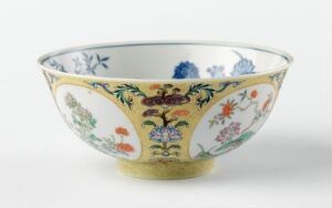  An elegant bowl with a yellow background and intricate floral patterns in cobalt blue, violet, green, pink, and orange. The inside is white with sparse floral designs, and the bowl rests on a plain background. Artist and title are unknown.