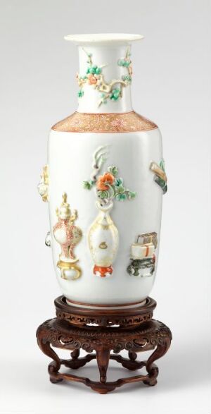  A tall, white porcelain vase with colorful bird and floral paintings, resting on a dark, intricately carved wooden stand.