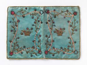  Antique textile with mirror-image floral embroidery in gold, red, and green on a muted turquoise background, possibly a purse or book cover.