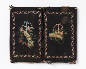  An open book or folio displaying two dark textile panels with colorful embroidery. The left panel shows a bird with colorful plumage among flowers, and the right panel displays a basket filled with a variety of flowers. Both panels are surrounded by a light brown vine-like border.