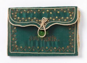  A small antique dark green wallet or photo album cover with gold dot patterns, an embossed word "SOUVENIR" in gold, and a twisted string loop closure with a matching green bead/button.