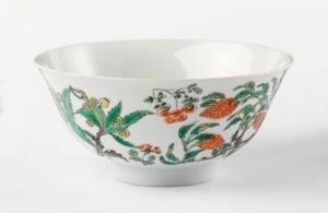  A porcelain bowl with a flared rim, illustratively painted with flowers and foliage in vibrant greens, reds, and oranges on a glossy white background. The bowl's interior remains plain, emphasizing the elaborate exterior decoration.