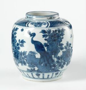  An antique ceramic vase with a blue and white color scheme, featuring a beautifully detailed peacock design surrounded by floral patterns, characteristic of traditional blue-and-white porcelain craftsmanship.