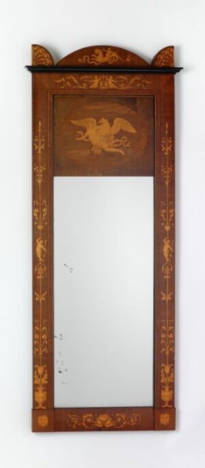  A tall, narrow decorative mirror with a rich brown wooden frame featuring a stylized bird motif at the top and ornate geometric patterns along the sides.